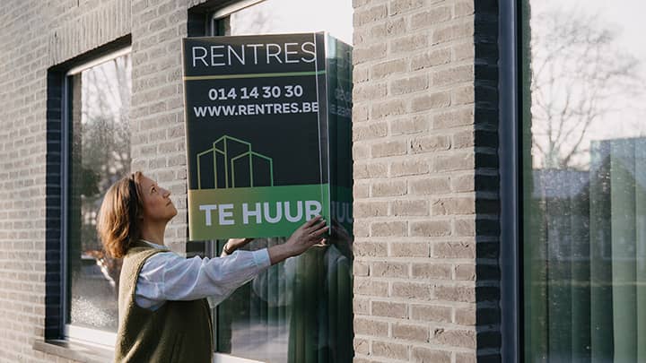 Rentres rentmeester commercieel beheer met An Vissers die een te huur bord bevestigt op een opbrengsteigendom